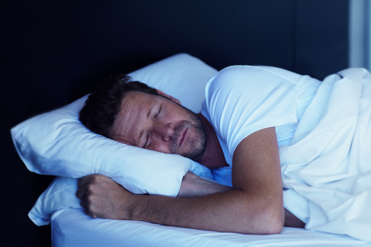 Man sleeping on his side, hugging a pillow in bed.